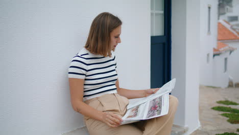 relaxed girl read newspaper on old town street. carefree tourist enjoy morning