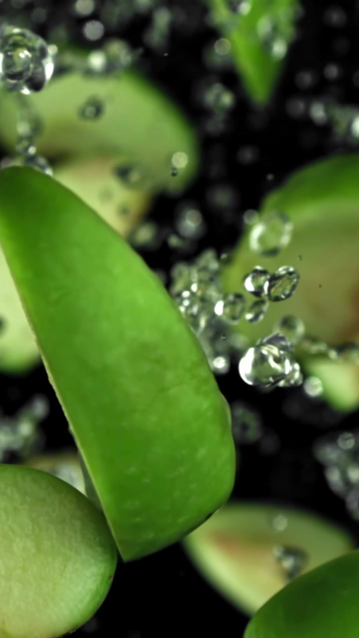Fette di mela verde fresca che schizzano nell'acqua
