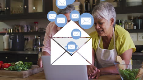 animation of envelope mail icons over senior couple using laptop at home