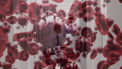 Animation-of-virus-and-blood-cells-over-caucasian-workers-in-server-room