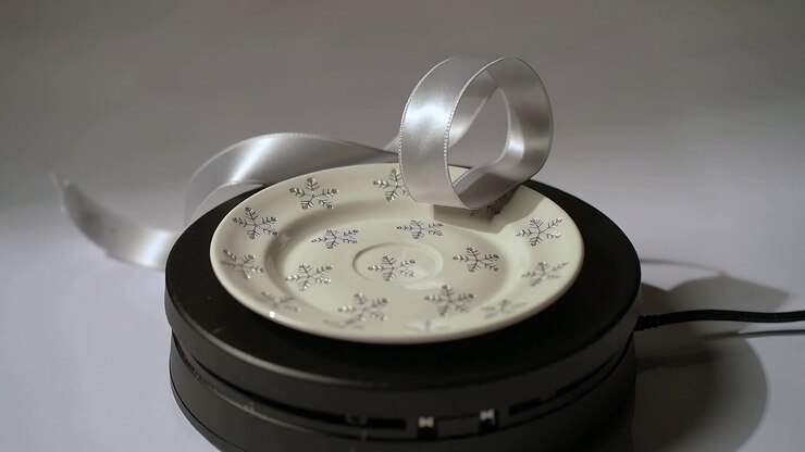 Rotating after power on floral saucer with silver ribbon spinning on table base with cord visible