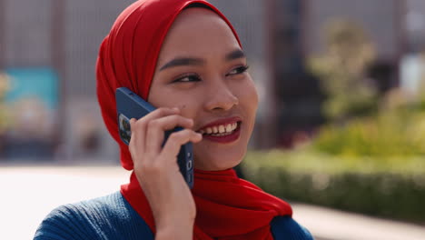young woman in red hijab on a phone call outdoors