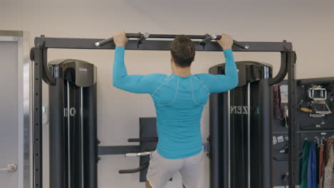 french man at the gym exercising on pull-up bar, doing wide-grip pull-up to strengthen back and shoulder