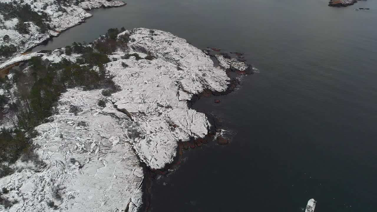 Aerial of coastline with snow on rocks and waves. In Norway 4K