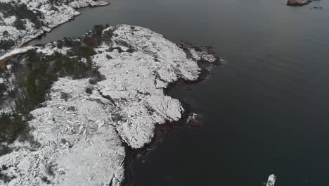 aerial of coastline with snow on rocks and waves. in norway 4k