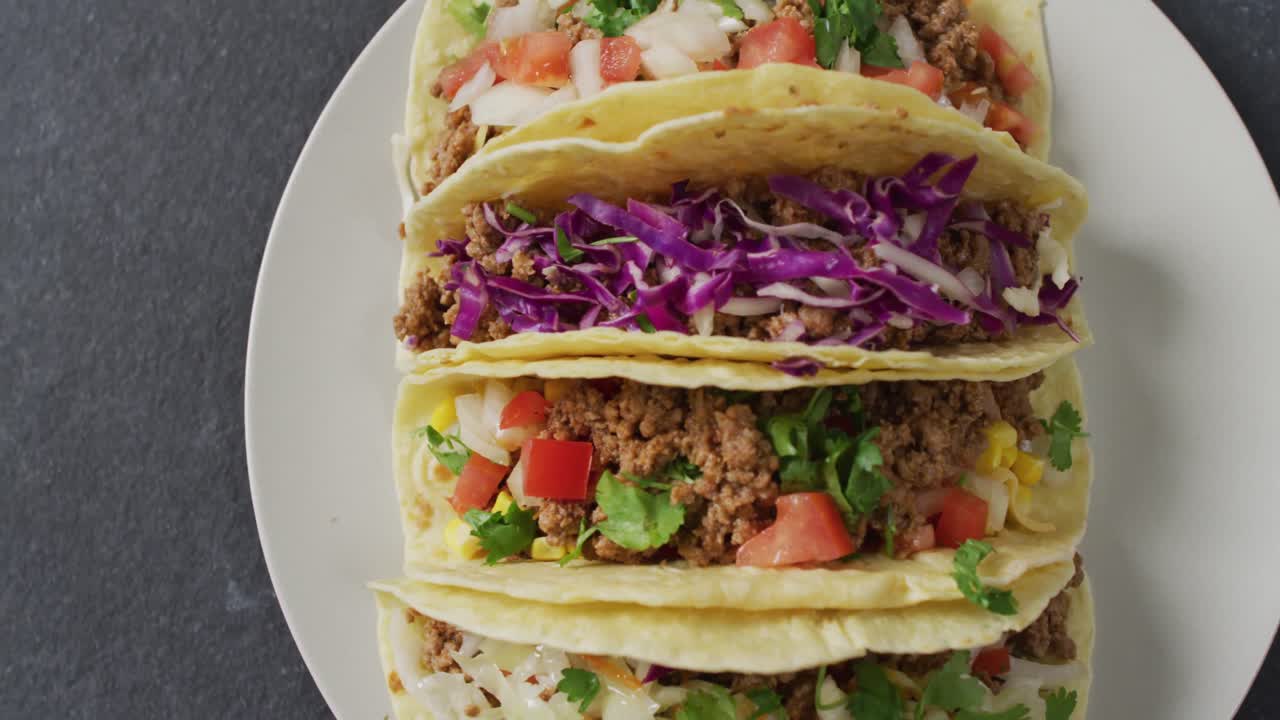 video de tacos recién preparados en un plato sobre un fondo gris