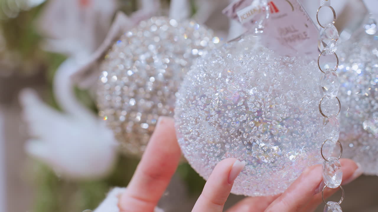 Close up hand view of person touching sparkling decorative material in home decor shop, beautiful shiny ornaments and decor items displayed for holiday season shopping