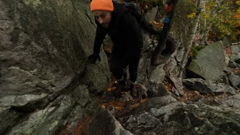 el joven está cansado de escalar rocas en el colorido bosque de otoño, sartén de mano