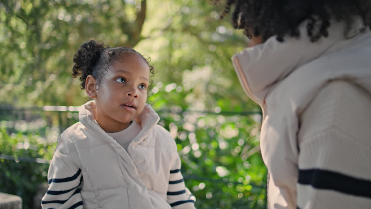 niña pasando tiempo con su madre sentada en el banco del jardín verde de cerca.