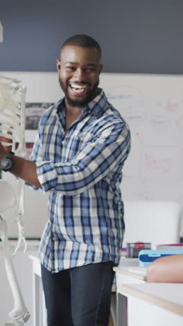 Video of happy african american teacher with class of diverse pupils during anatomy lesson