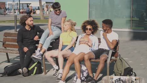 lounging diverse friends on bench in sunshine