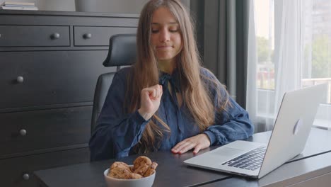 retrato de una mujer a dieta en la oficina tentada a comer galletas en el escritorio mientras trabaja