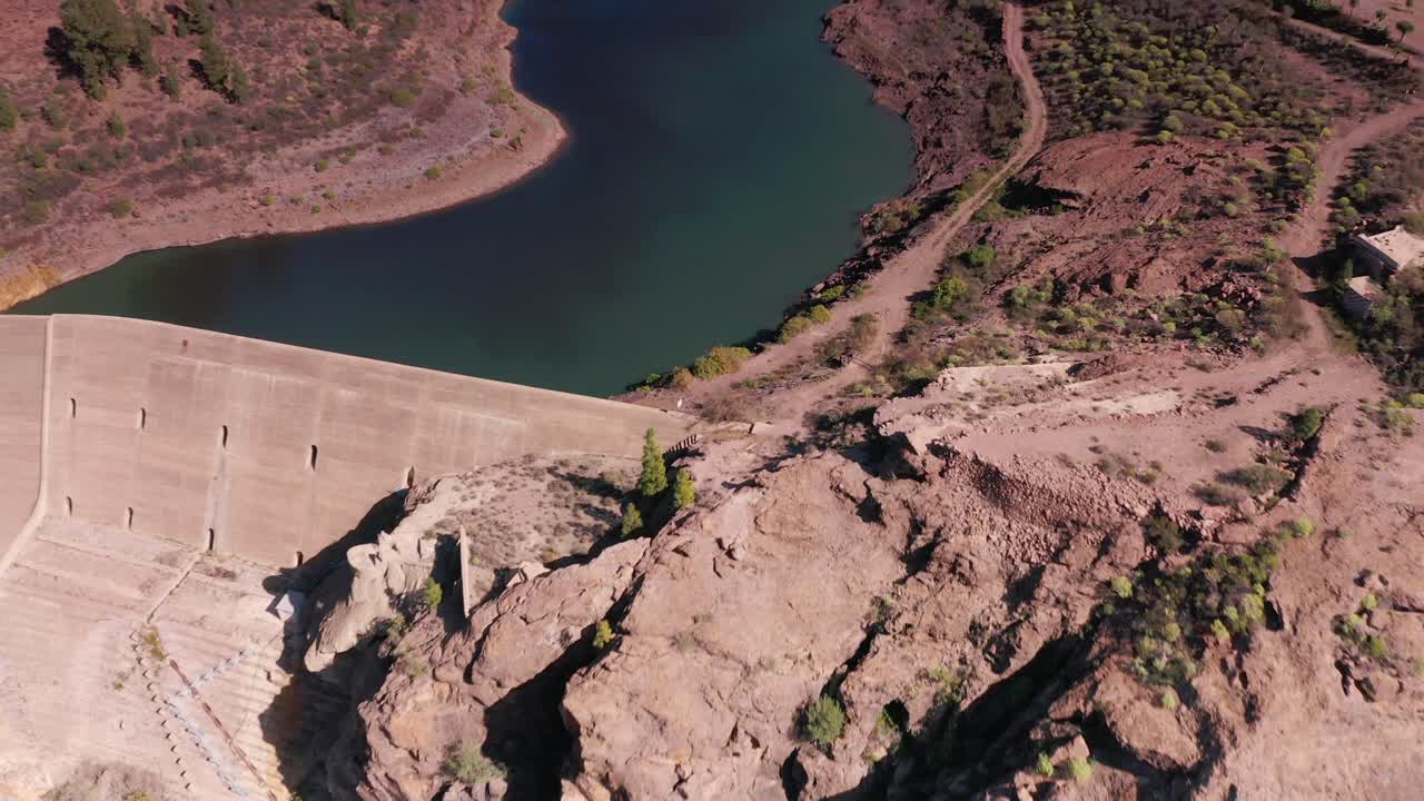 drone aéreo volando bajo sobre una presa sobre un embalse de lago en las montañas de gran canaria, españa