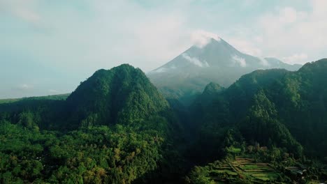 Revelan-Una-Toma-De-Un-Dron-De-La-Selva-Tropical-Cubierta-De-Vegetación-En-La-Colina-Y-Un-Gran-Valle-Con-Un-Volcán-En-El-Fondo