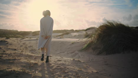 turista tranquilo caminando por las dunas de la playa a la luz del sol de la mañana. modelo sereno contemplando