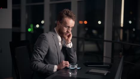 handsome-man-working-in-the-office-at-the-table-drinking-water