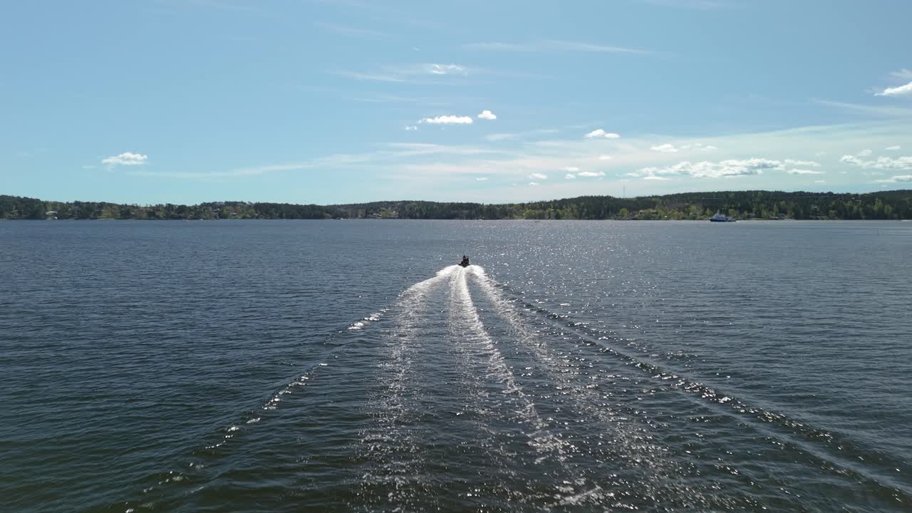Aerial shot following a speed boat on the ocean on a summer day.