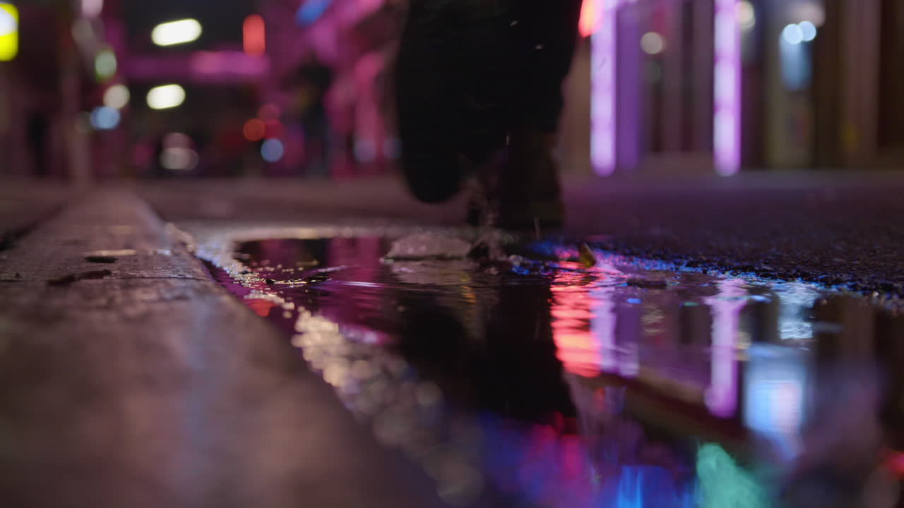 Man stepping into muddy puddle at night time in neon lit street Reeperbahn Hamburg St Pauli Grosse Freiheit Germany Red Light District Nightlife