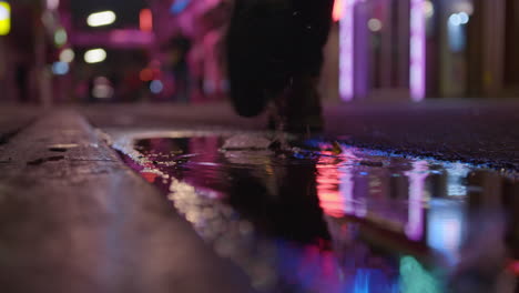 man stepping into muddy puddle at night time in neon lit street reeperbahn hamburg st pauli grosse freiheit germany red light district nightlife