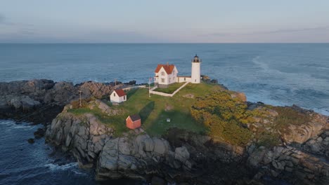 Luftdrohnenaufnahme-Von-York-Beach-Maine,-Der-Bei-Sonnenuntergang-Um-Den-Cape-Neddick-Nubble-Lighthouse-Fliegt