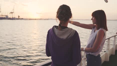 two girlfriends dancing on the deck of the ship at sunset