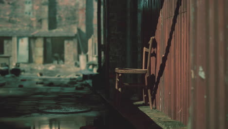 a lone wooden chair sits in an abandoned alleyway