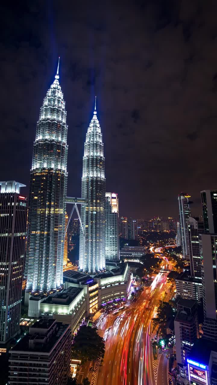 Petronas Twin Towers glowing against the night sky, vibrant light trails from passing cars streaking along the highway in Kuala Lumpur, Malaysia, showcasing a stunning urban landscape