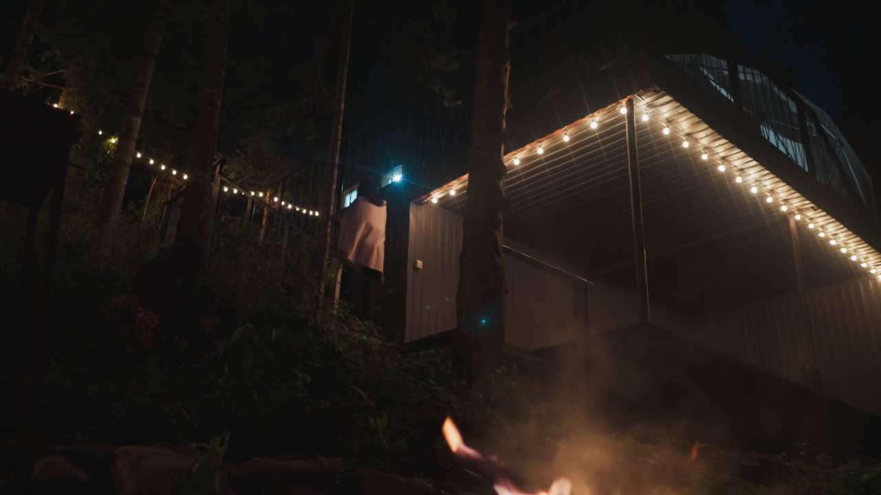 joven sube la escalera en el patio. territorio aislado perteneciente a un retiro rural para viajeros en la densa extensión de bosque. fogata crepitante