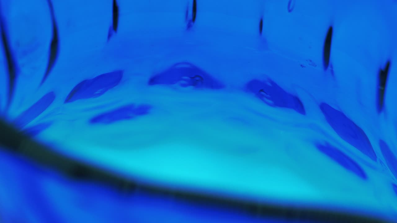 Vetreria blu astratta rotante per interni su sfondo bianco in loop.