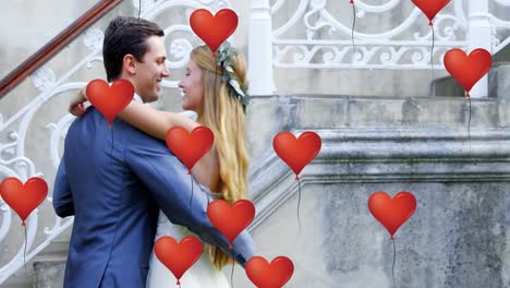 multiple heart balloons floating against new married couple dancing