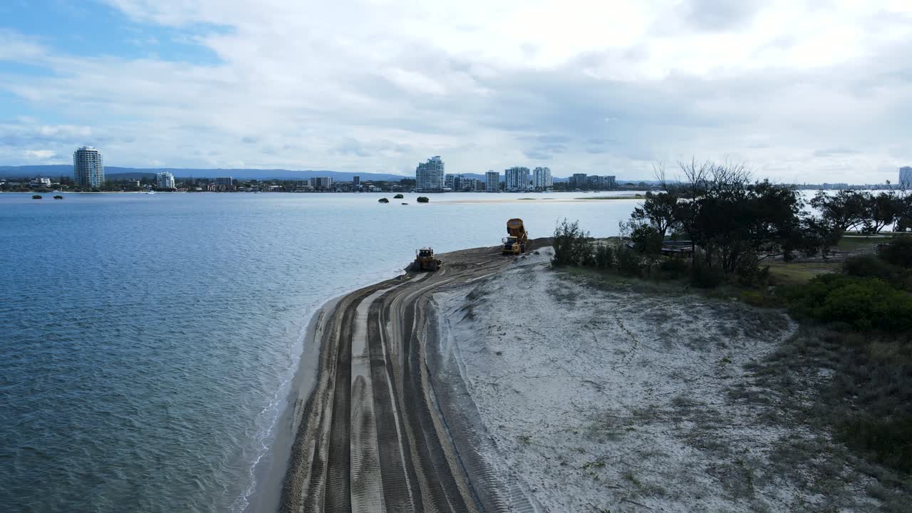 해안 침식 프로젝트를 위해 모래를 움직이는 해변에서 작업하는 무거운 기계의 드론 뷰를 드러내는