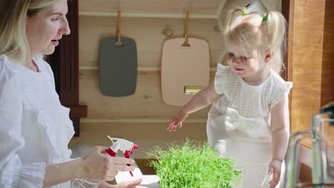 mother and daughter watering plants in kitchen