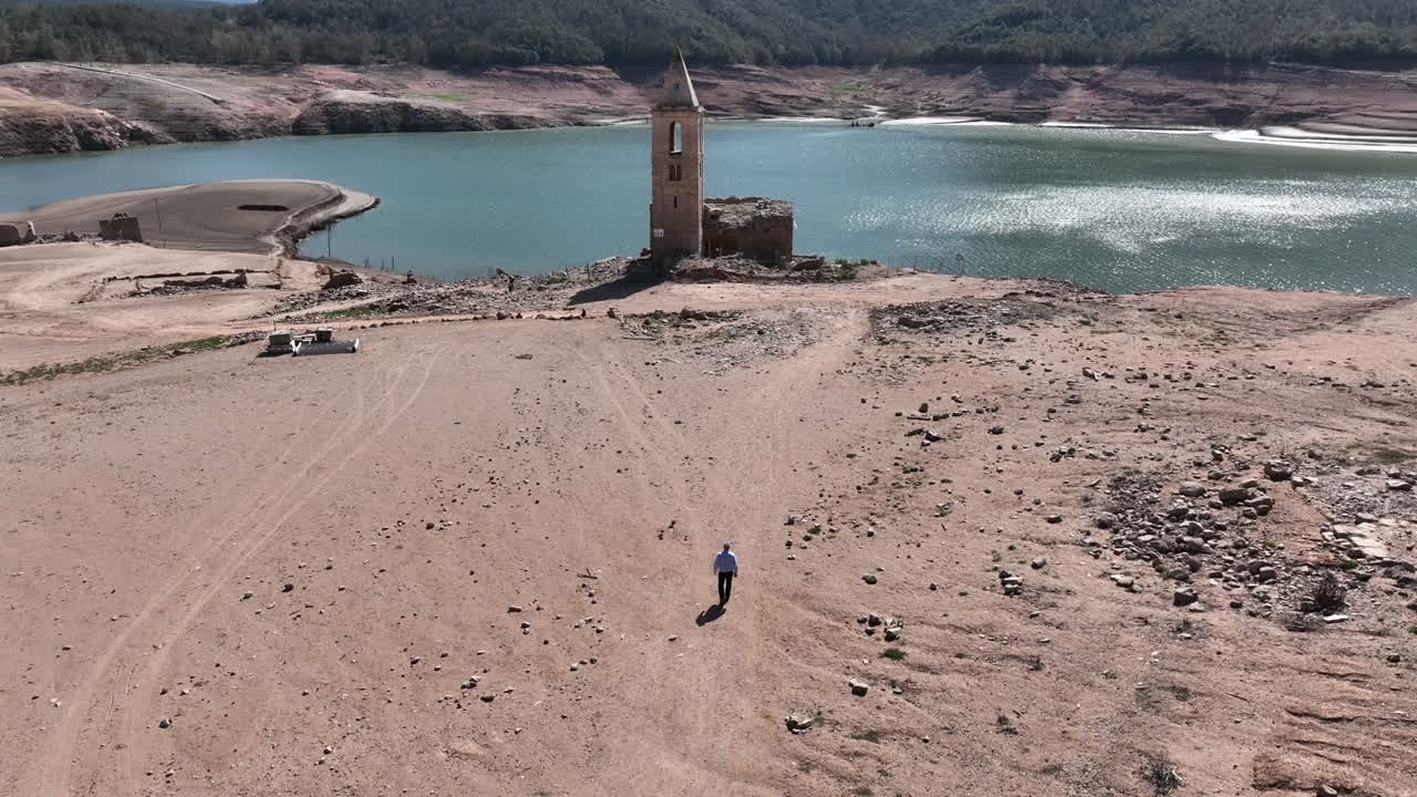persona solitaria caminando hacia la vieja iglesia cerca del lago seco, vista aérea de avión no tripulado