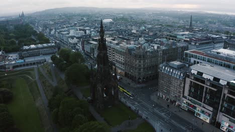 Early-morning-view-of-the-Scott-Monument-in-Edinburgh,-Scottland-with-a-public-transit-train-passing-underneath