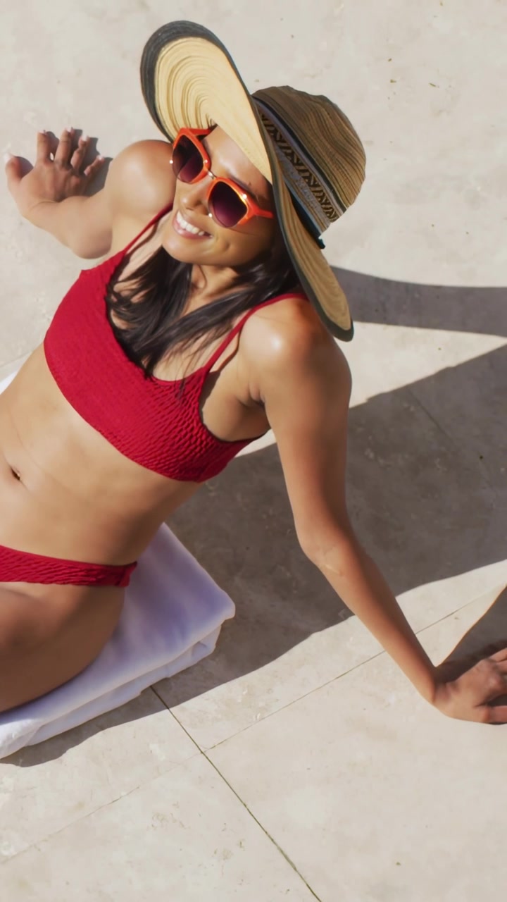Vertical video: Woman reclining on deck in hat as midway UI icons forming tech network over her