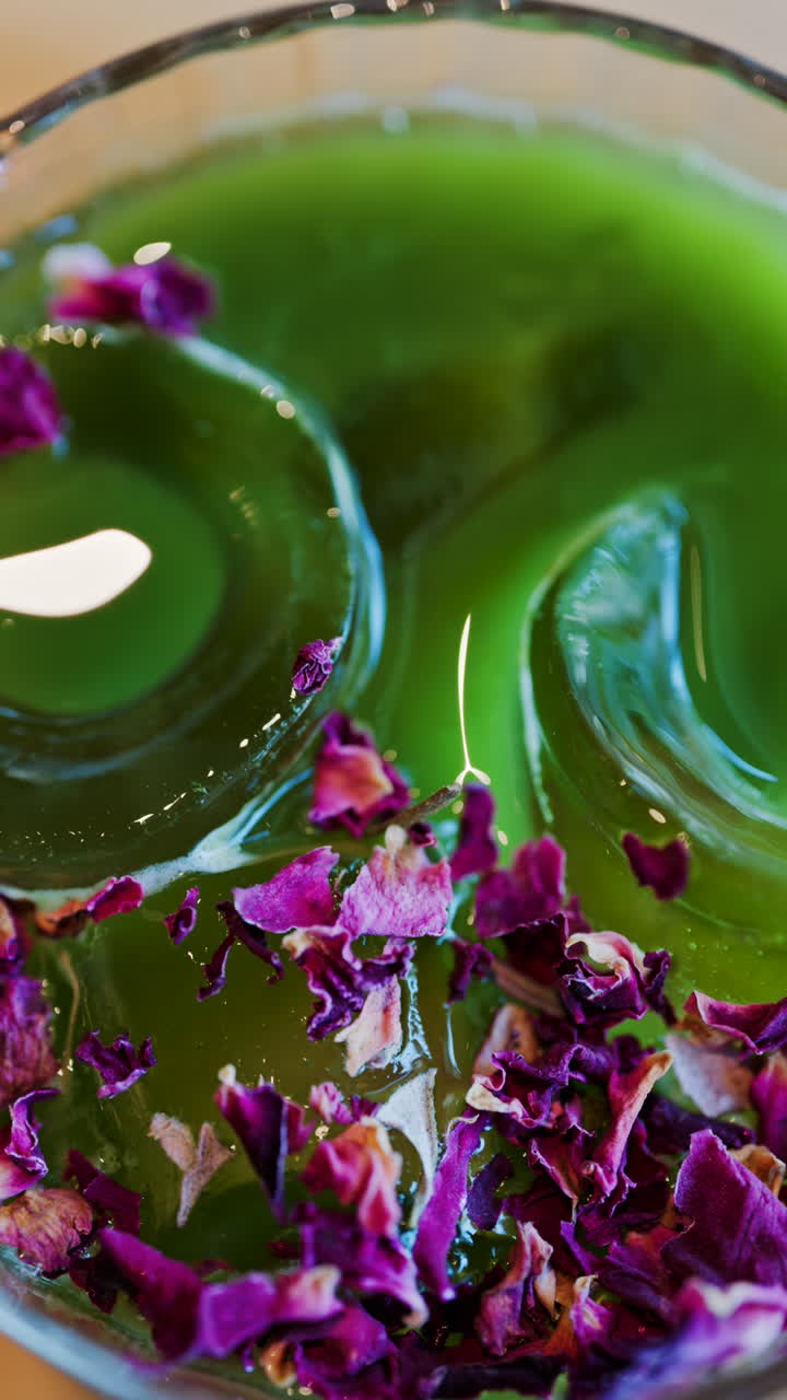 Close up of an iced matcha in a glass with purple dried flowers on top. Vertical