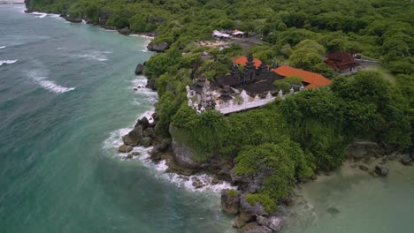 toma panorámica de drones de un complejo de templos gigantes entre la naturaleza verde en un acantilado