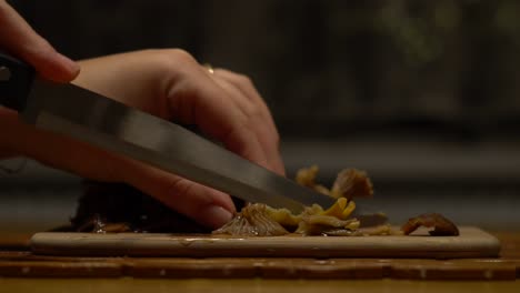 mujeres caucásicas cortando champiñones chanterelle de embudo en una tabla de cortar