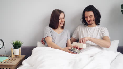 couple opening a gift in bed