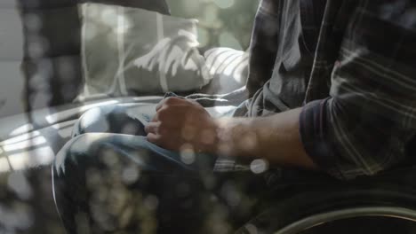animation of light spots over disabled caucasian man sitting in wheelchair