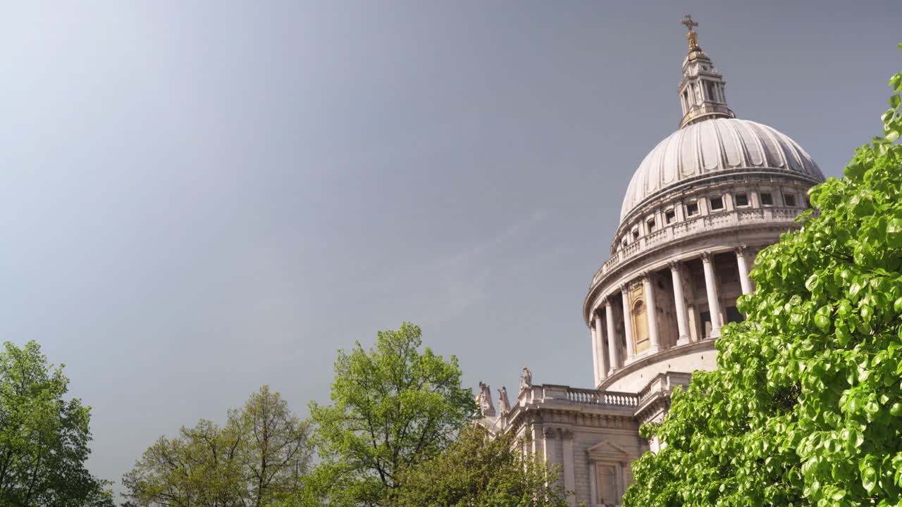 Beautiful view of famous St. Paul church's dome with trees in the foreground during daytime as the wind slowly blowing the leaves
