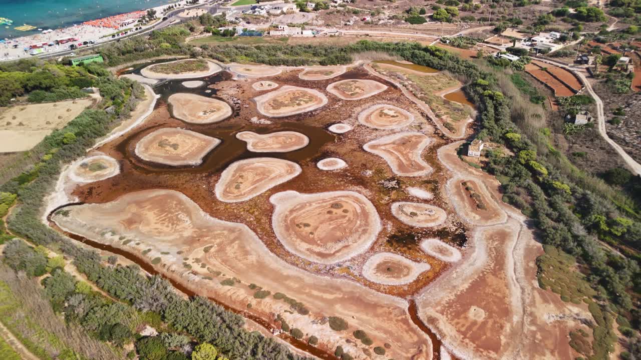 Aerial view of rugged terrain with water patches by a coastal town