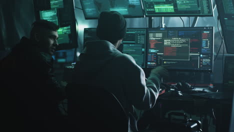 hackers or cybersecurity professionals working in a multi-screen control room