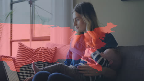 rutas de luz sobre el mapa del mundo contra la mujer sosteniendo al bebé usando una computadora portátil en casa