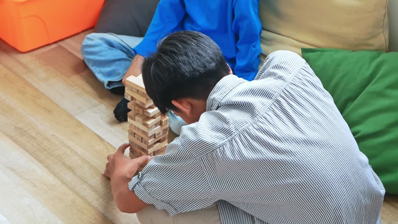 Brothers concentrate intensely playing tower stacking game indoors
