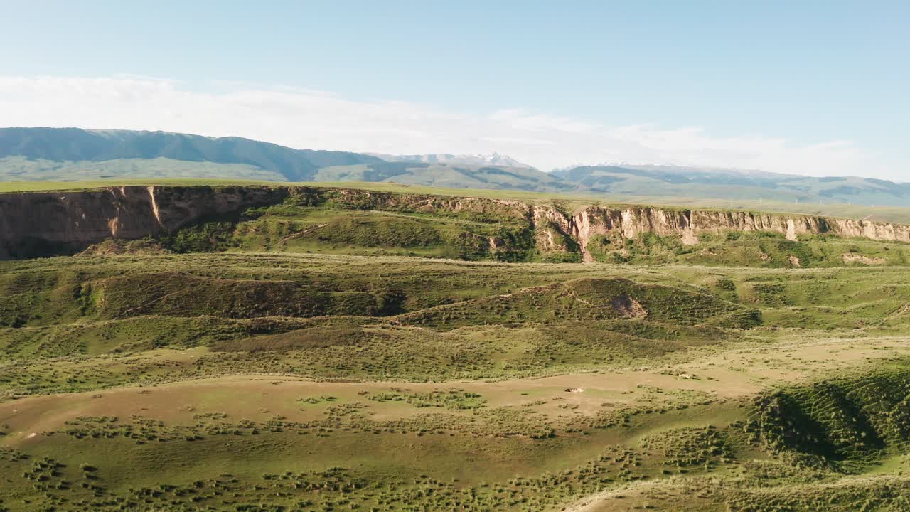 горные вершины и луга под белыми облаками.