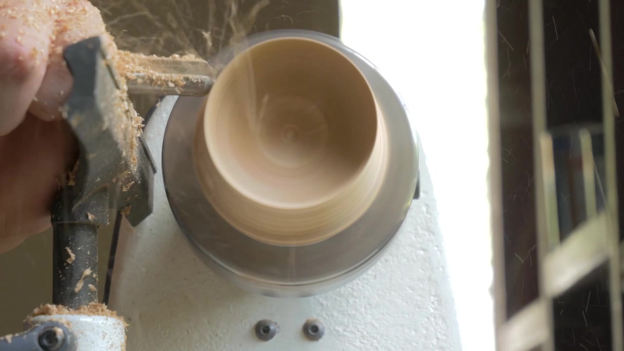 Uomo che usa un tornio per legno per realizzare una tazza di legno