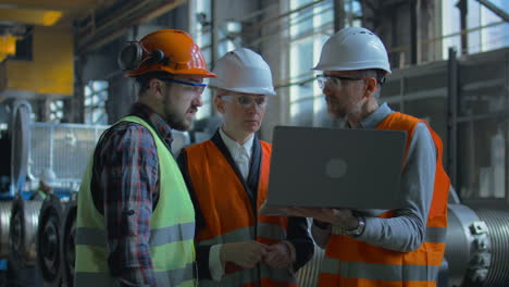 factory workers discussing project on laptop