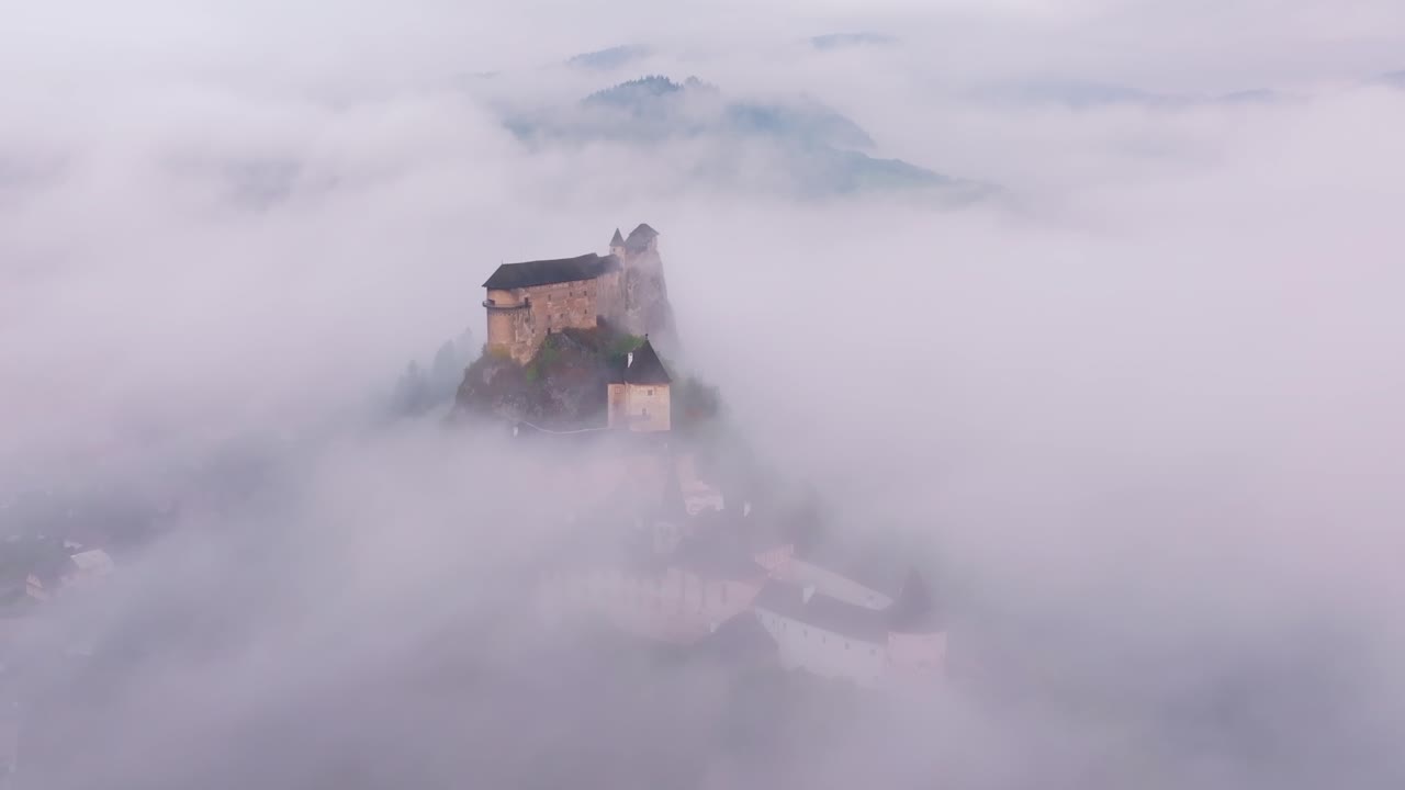 Drone capture of Orava Castle enveloped in golden morning mist