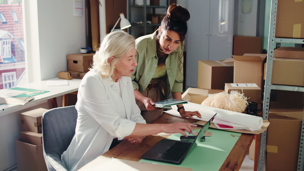 Due donne che collaborano su laptop e tablet in un ufficio di piccola impresa